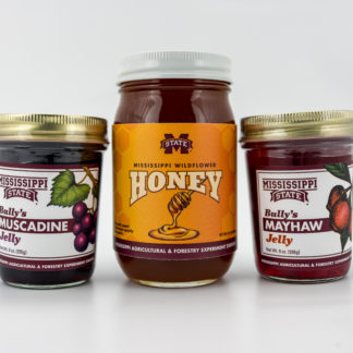 Muscadine jelly in a 9oz jar, 22 oz jar of wildflower honey, and 9 oz jar of mayhaw jelly