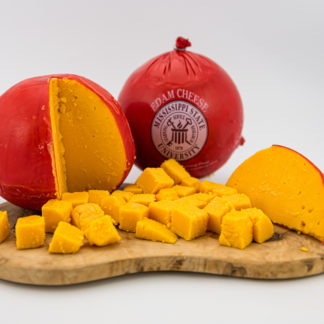 3 lb Edam Cheese Ball cubed on a cutting board, with wedge of Edam and ball in the background