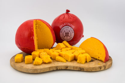 3 lb Edam Cheese Ball cubed on a cutting board, with wedge of Edam and ball in the background