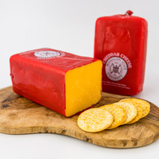 2 lb cheddar cheese block on a cutting board with crackers