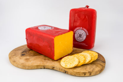 2 lb cheddar cheese block on a cutting board with crackers